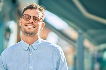Young hispanic businessman smiling happy standing at the city.