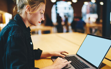 Caucaisan woman browsing website via blank laptop computer with copy space area for internet advertising, skilled freelancer chatting and messaging via netbook with mock up screen for your website