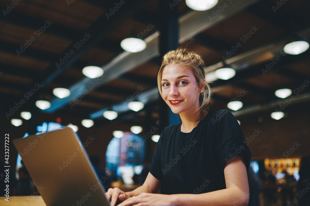 Poster portrait of happy caucaisan copywriter smiling at camera while doing distance job in coworking space