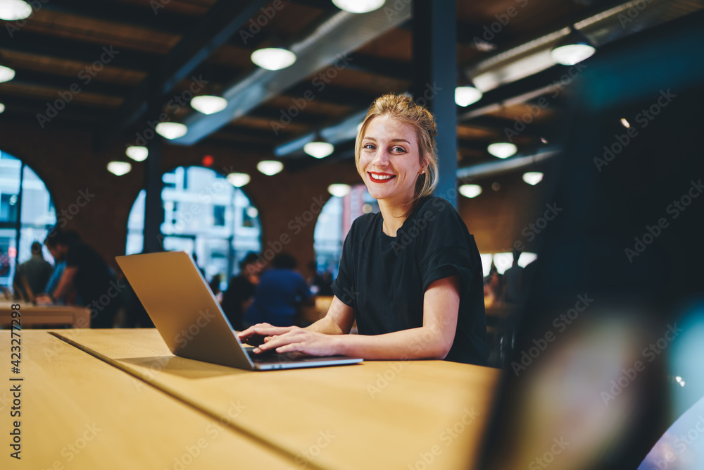 Poster portrait of happy caucaisan copywriter smiling at camera while doing distance job in coworking space