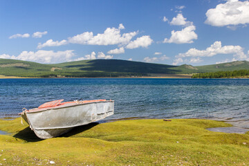 One old boat on the bank of the lake and green forest behind, Khovsgol lake, Mongolia