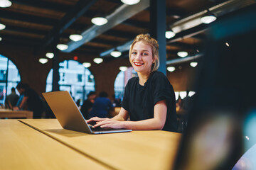 Portrait of happy Caucaisan copywriter smiling at camera while doing distance job in coworking...