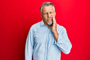 Middle age grey-haired man wearing casual clothes touching mouth with hand with painful expression because of toothache or dental illness on teeth. dentist