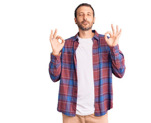 Young handsome man wearing casual clothes relaxed and smiling with eyes closed doing meditation gesture with fingers. yoga concept.