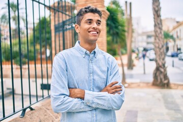 Young latin man smiling happy walking at the city.