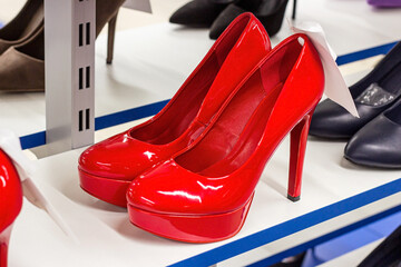 New elegant red women shoes on the retail clothing shop display shelf.