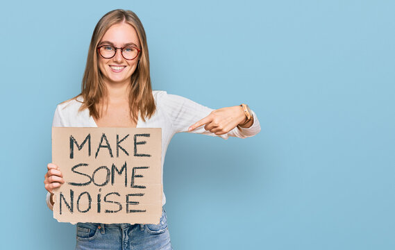 Beautiful blonde woman holding make some noise banner smiling happy pointing with hand and finger