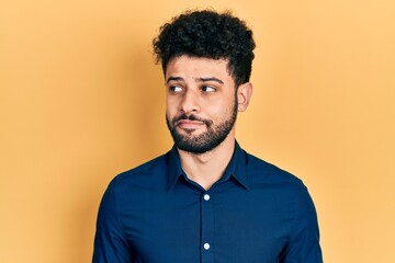 Young arab man with beard wearing casual shirt smiling looking to the side and staring away thinking.