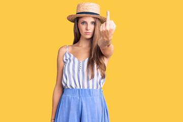 Young beautiful blonde woman wearing summer hat showing middle finger, impolite and rude fuck off expression