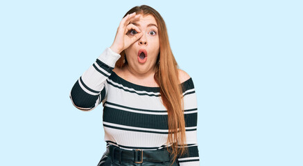 Young beautiful redhead woman wearing elegant clothes doing ok gesture shocked with surprised face, eye looking through fingers. unbelieving expression.