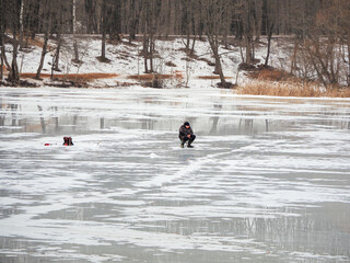 Dangerous fishing on wet spring ice. Fisherman on wet melting ice.