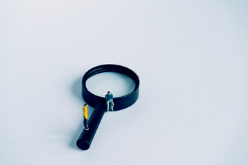 Two miniature on a magnifying glass. Yellow figure is the investigator and the sitting figure is...
