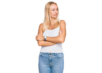 Young blonde girl wearing casual style with sleeveless shirt looking to the side with arms crossed convinced and confident