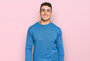 Hispanic young man wearing casual clothes looking positive and happy standing and smiling with a confident smile showing teeth