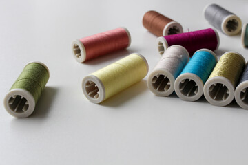 The spools of colorful thread on the white background. Selective focus.