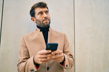 Handsome business man wearing elegant jacket using smartphone outdoors