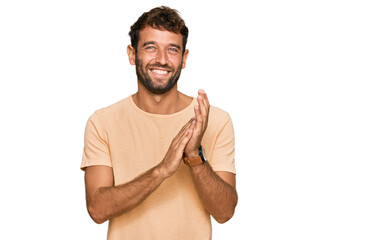 Handsome young man with beard wearing casual tshirt clapping and applauding happy and joyful, smiling proud hands together