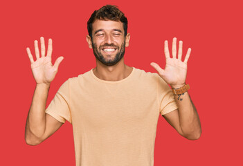 Handsome young man with beard wearing casual tshirt showing and pointing up with fingers number ten...