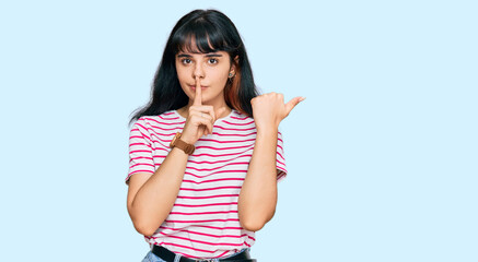 Young hispanic girl wearing casual clothes asking to be quiet with finger on lips pointing with hand to the side. silence and secret concept.