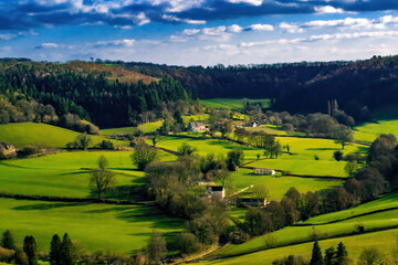 Beautiful green hills in Gloucestershire. Meadows surrounded by trees along which the road leads to the village. The vivid blue sky intensifies the idyllic atmosphere of the landscape.