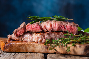 Ready beef steak with rosemary on blue background