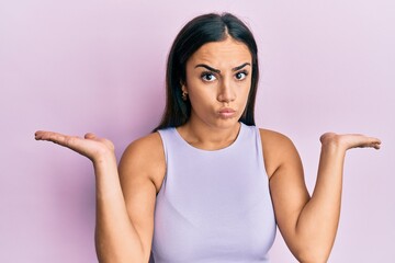 Fototapeta premium Young brunette woman wearing casual clothes clueless and confused with open arms, no idea and doubtful face.