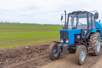 Obraz premium Agricultural tractor in the field. The tractor is ready to work in the field. Spring.