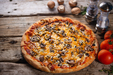 Pizza ready with mushrooms and tomatoes and spices on a wooden background