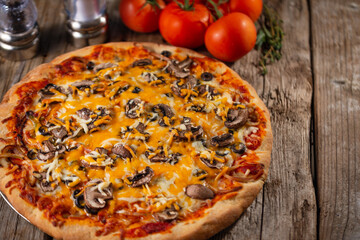Pizza ready with mushrooms and tomatoes and spices on a wooden background