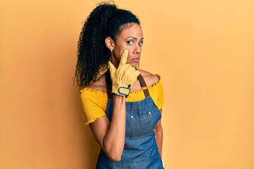 Middle age african american woman wearing professional apron pointing to the eye watching you gesture, suspicious expression