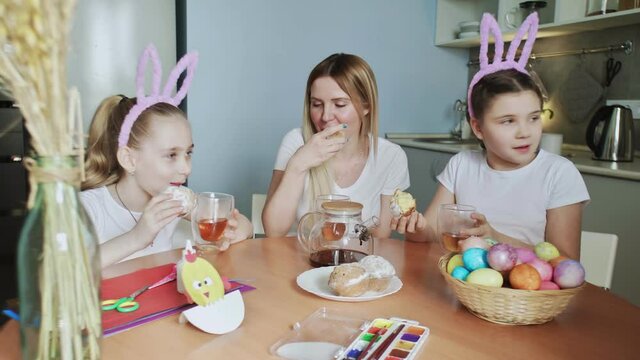 Happy Easter. Preparing the family for Easter. Mother and her little daughters drink tea and eat muffins