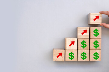 concept of revenue growth. growth on stacked wooden cubes on gray background. Financial or business growth concept. arrows and dollar icons on wooden cubes 