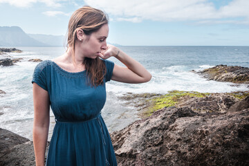 woman in blue summer dress overlooking the sea