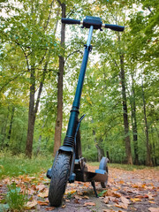 Black electric scooter close-up in the forest. A healthy enjoyable hobby.