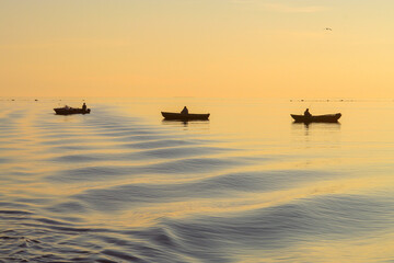 Fishermen in their boats in the White Sea near Solovki islands during sunset