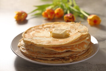 pancakes on a white plate with butter on a background of yellow flowers