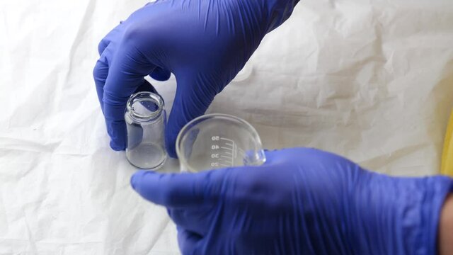 glass medical bottle with liquid in doctor laborant hands in medical blue gloves, laboratory testing of vaccine or clinic of samples for spectrophotometric analysis and experiments, medical research, 