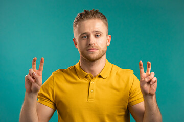 Handsome man showing with hands and two fingers air quotes gesture, bend fingers isolated over blue background. Not funny, irony and sarcasm concept. - obrazy, fototapety, plakaty