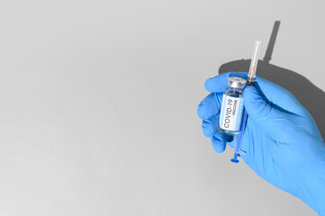 Coronavirus vaccination concept. Hand in medical glove holds syringe and ampoule with the vaccine...
