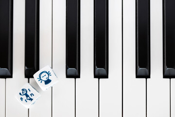 Fototapeta premium Two dices with depiction of dancing and listening to music on piano keyboard. Closeup