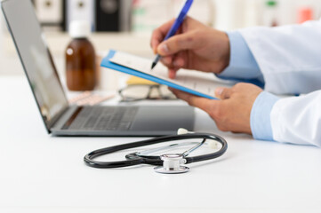 Cropped shot of a stethoscope with clipboard and laptop on desk,doctor working in hospital writing a prescription,healthcare and medical concept,test results