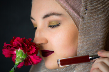 Woman with hijab, professional make-up, showing makeup items, black background, muslim girl