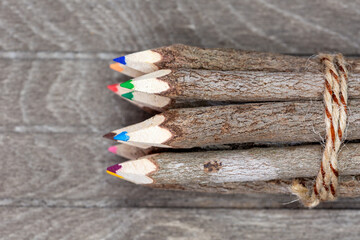 bound crayons made of real, untreated wood on top view with real tree bark on brown wooden board for artists, students and nature lovers