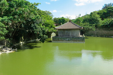 Fototapeta premium Green pond and old wooden building covered with traditional Japanese tiles in Ishigaki, Japan