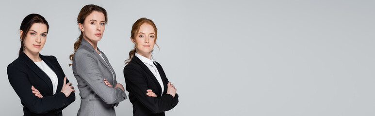 Pretty adult businesswomen looking at camera isolated on grey, banner