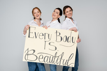 Adult women holding placard with every body is beautiful lettering isolated on grey