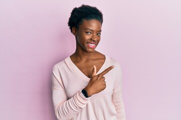 Young african american girl wearing casual clothes smiling cheerful pointing with hand and finger up to the side