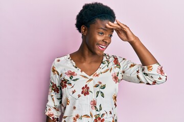 Young african american girl wearing casual clothes very happy and smiling looking far away with hand over head. searching concept.