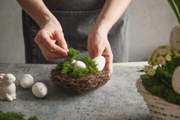 Easter floral DIY composition for table centerpiece with white eggs, moss and bunny. Close up.