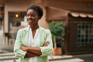 Young african american businesswoman with crossed arms smiling happy at the city